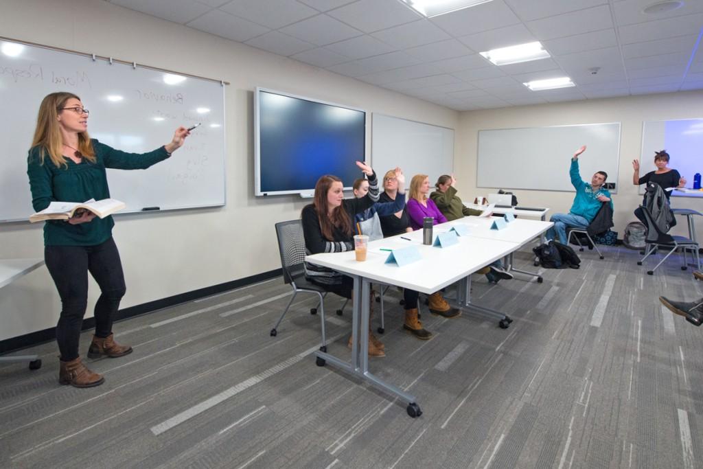 Students raise their hands to answer questions during a social justice class